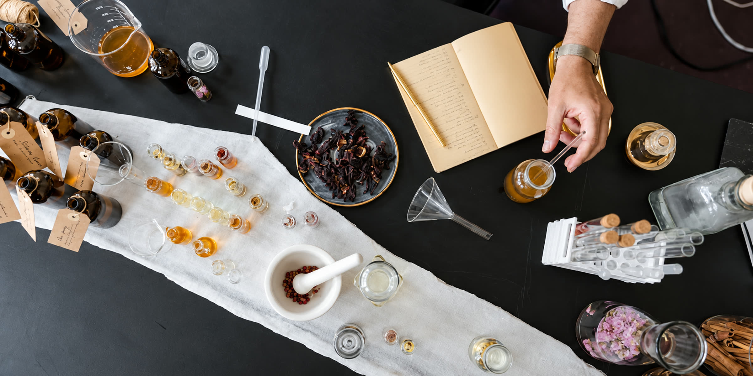 A perfumer blending oils at a worktable